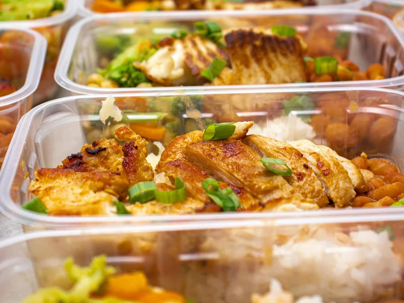 Meal prep containers with chicken, rice, beans, and vegetables